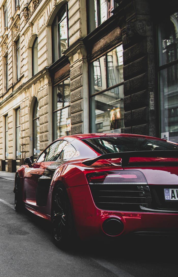 about-03 Sleek red sports car parked on a charming historic street in Prague, highlighting urban elegance and powerful design.