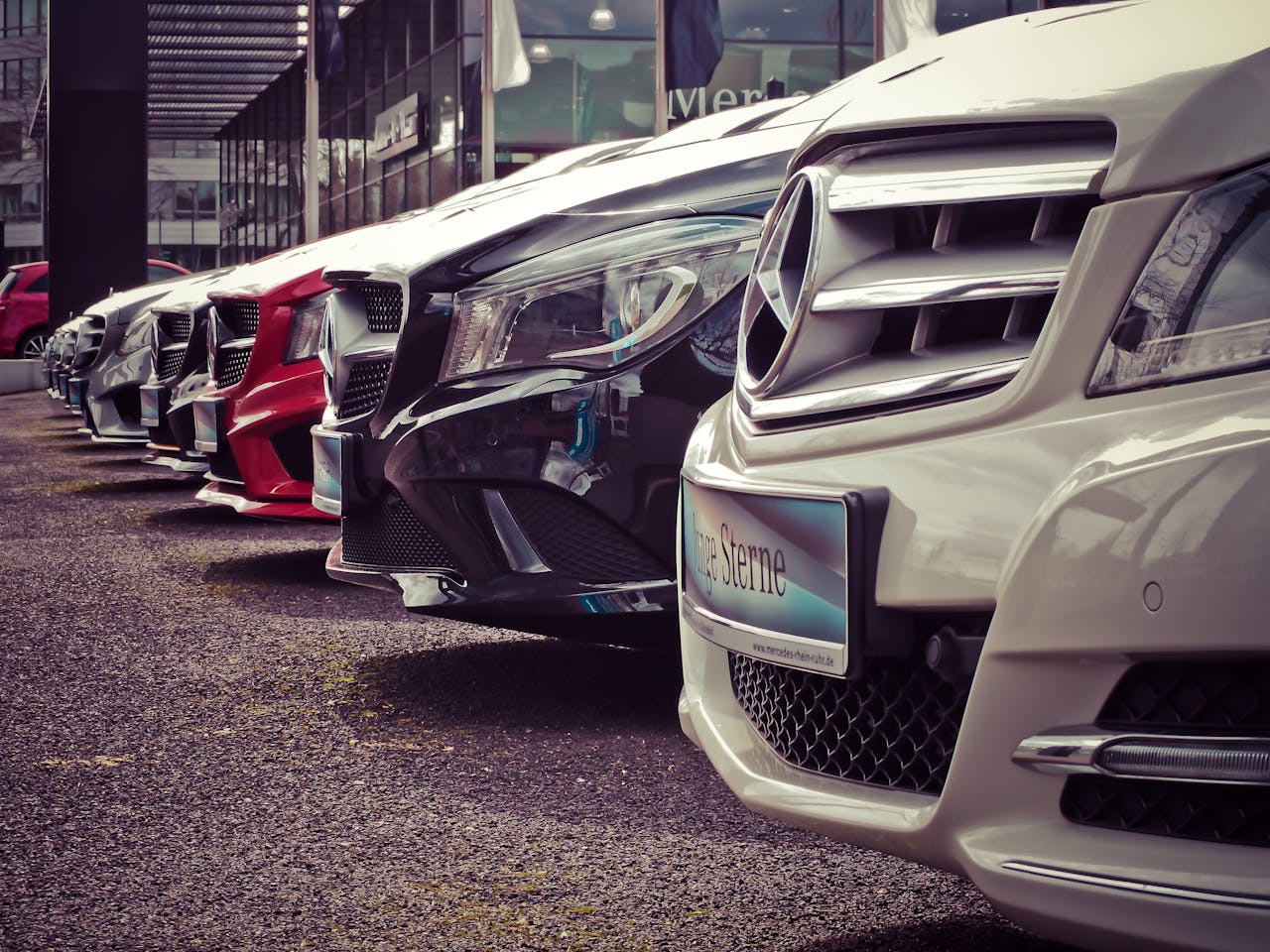 about-02 Luxury cars lined up at an outdoor dealership, showcasing sleek designs.